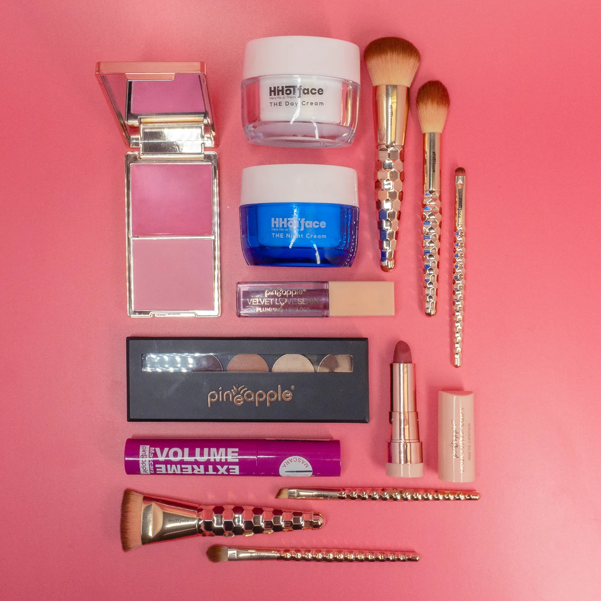 Cosmetic and makeup products laid out on a table with a pink background