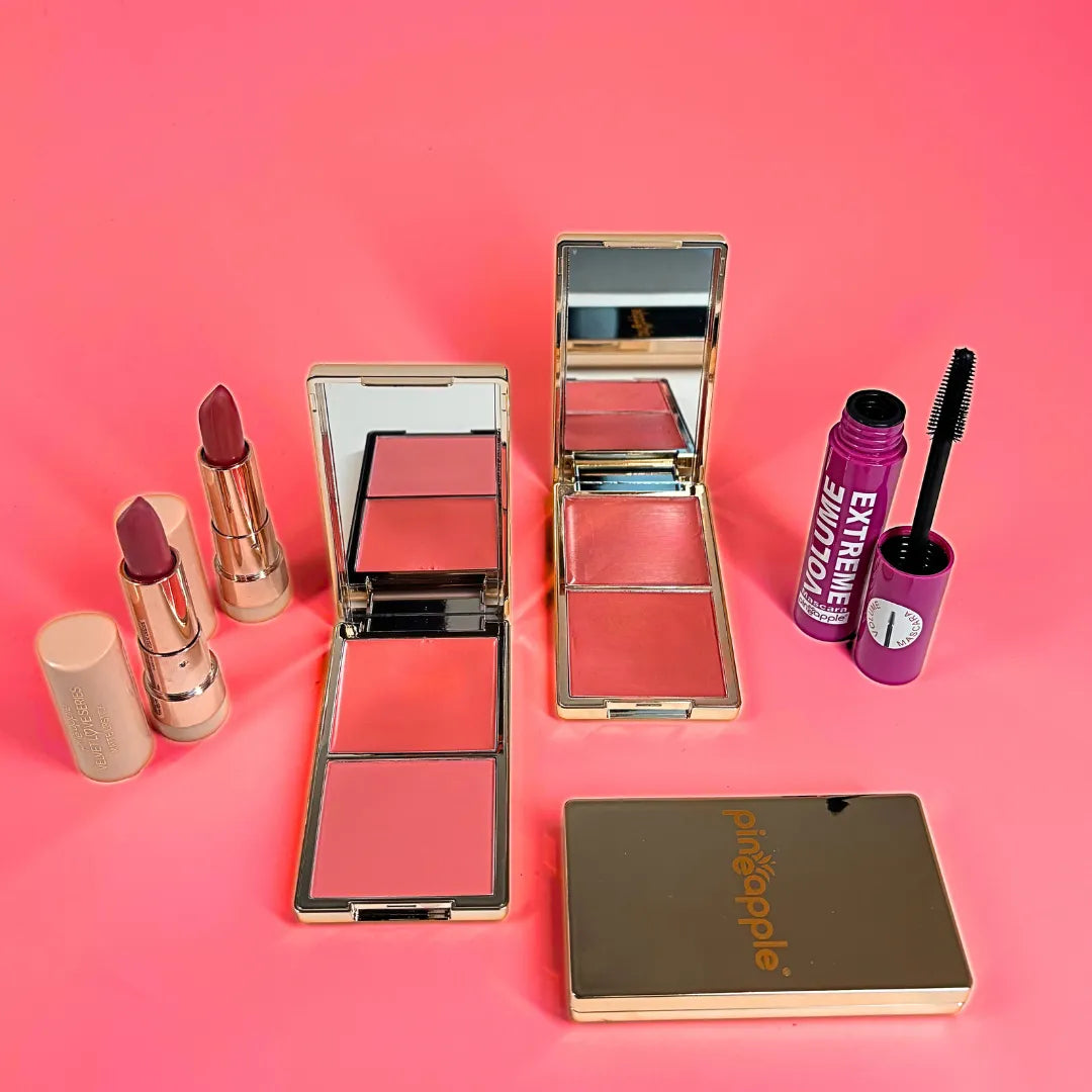 Makeup products including lipsticks, blushes, and a compact mirror on a pink background